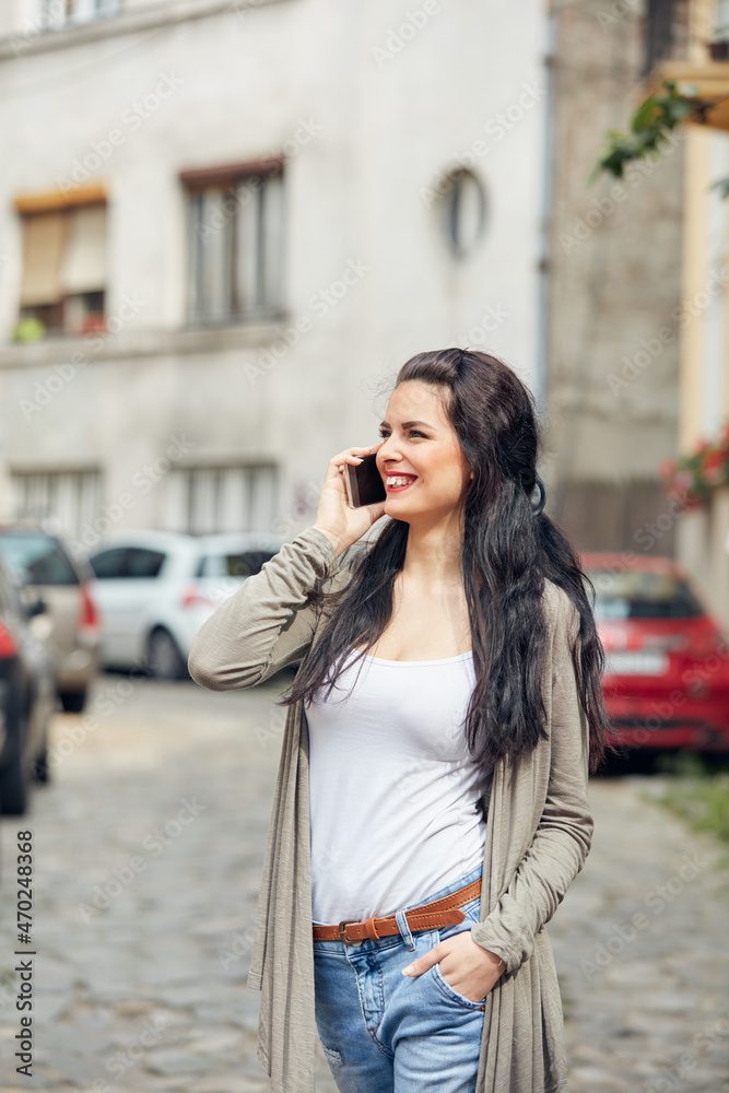 Young cute female using smartphone on the street.