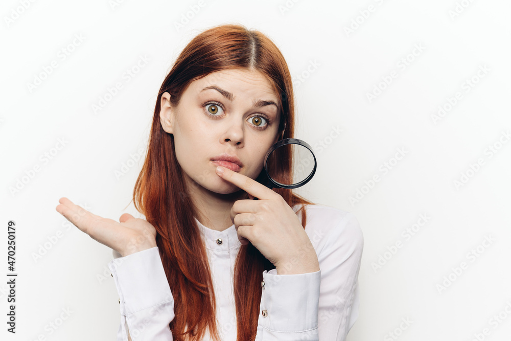 cheerful red-haired woman holding a magnifying glass near her face cheerful red-haired woman holding a magnifying glass near her face