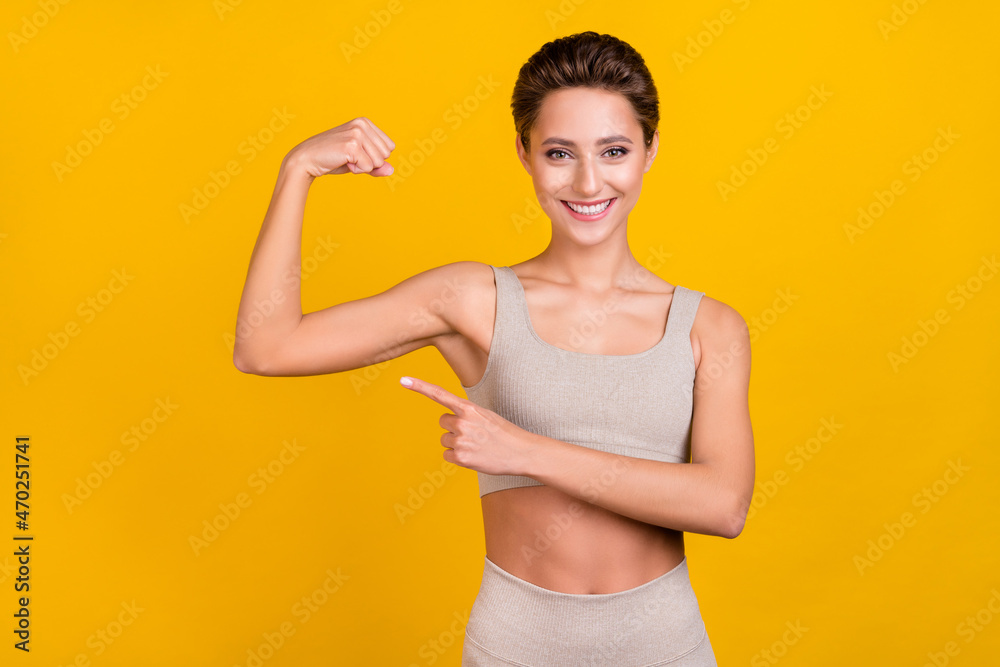 Photo of pretty strong lady direct finger strong biceps muscle wear grey top isolated yellow color background Photo of pretty strong lady direct finger strong biceps muscle wear grey top isolated yellow color background
