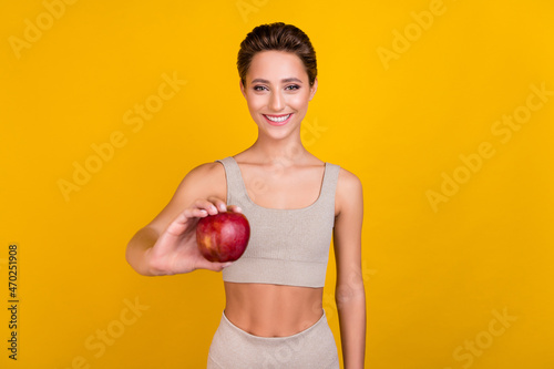 Photo of cheerful positive lady hold fresh natural apple wear grey cropped top isolated yellow color background