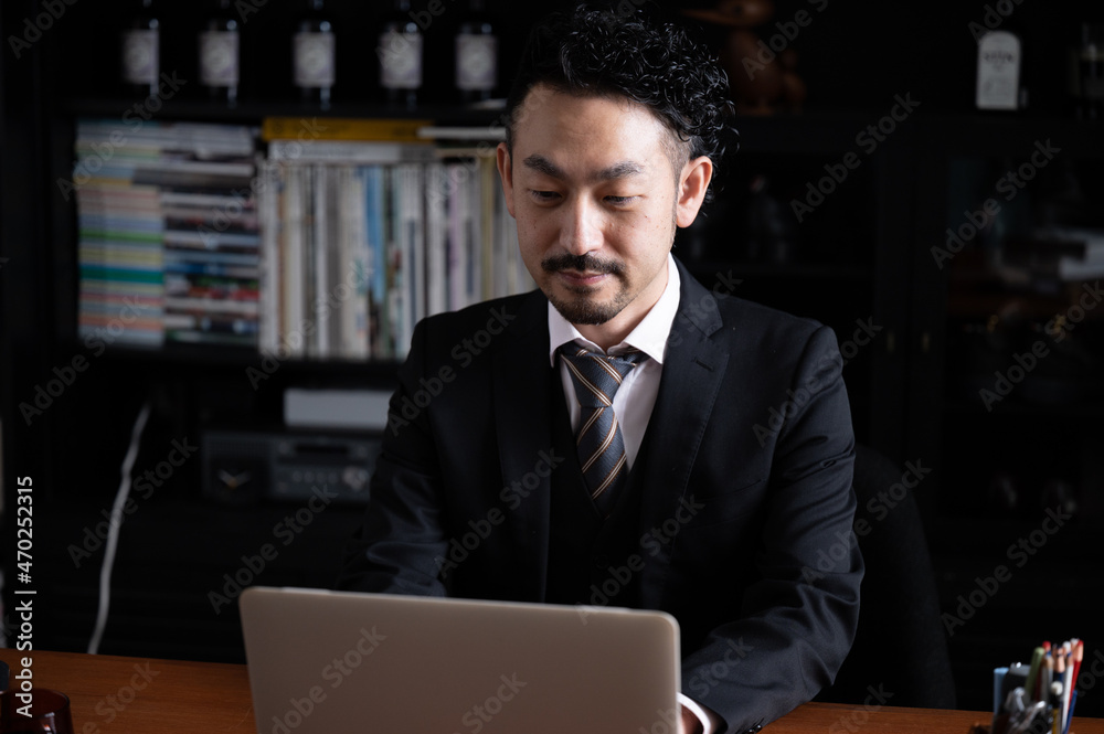 パソコンでうつむくハンサムなアジア人(日本人)ビジネスマン男性 左にコピースペースあり パソコンでうつむくハンサムなアジア人(日本人)ビジネスマン男性 左にコピースペースあり