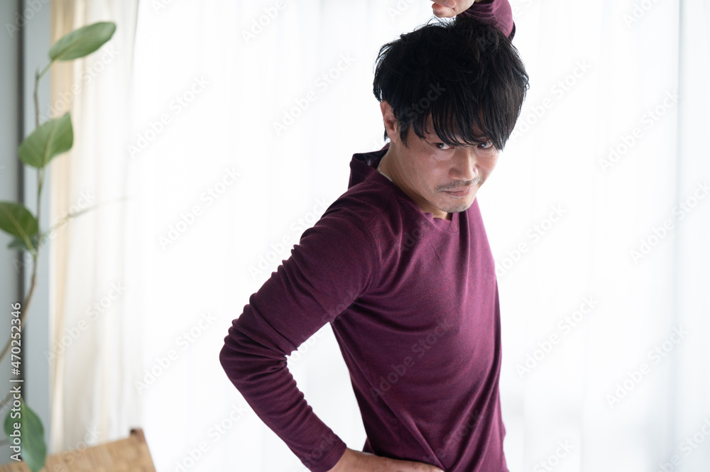 部屋の中で逆光の朝日を浴びてストレッチをするかっこいい日本人男性　クローズアップ