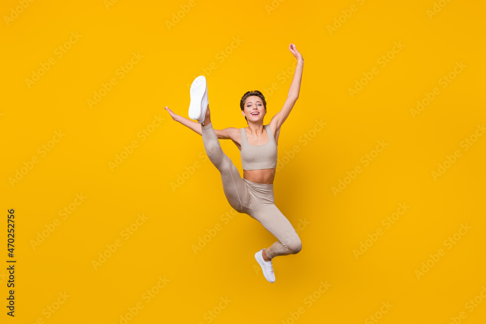 Full length body size view of pretty cheerful girl jumping working out shaping weight loss isolated over bright yellow color background