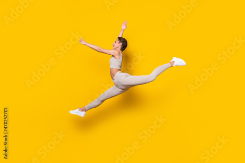 Profile photo of energetic active lady jump wear cropped top leggings sneakers isolated yellow color background