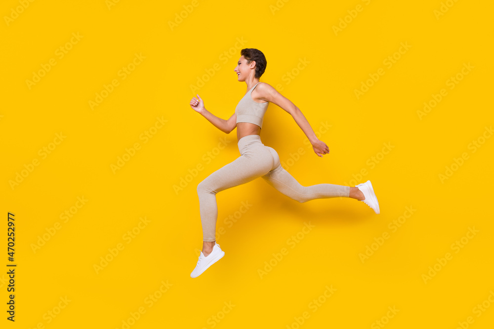 Profile photo of sportive runner lady jump run wear cropped top leggings shoes isolated yellow color background