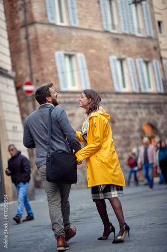 A young couple in love having a good time while walking the old city and chatting. Walk, rain, city, relationship
