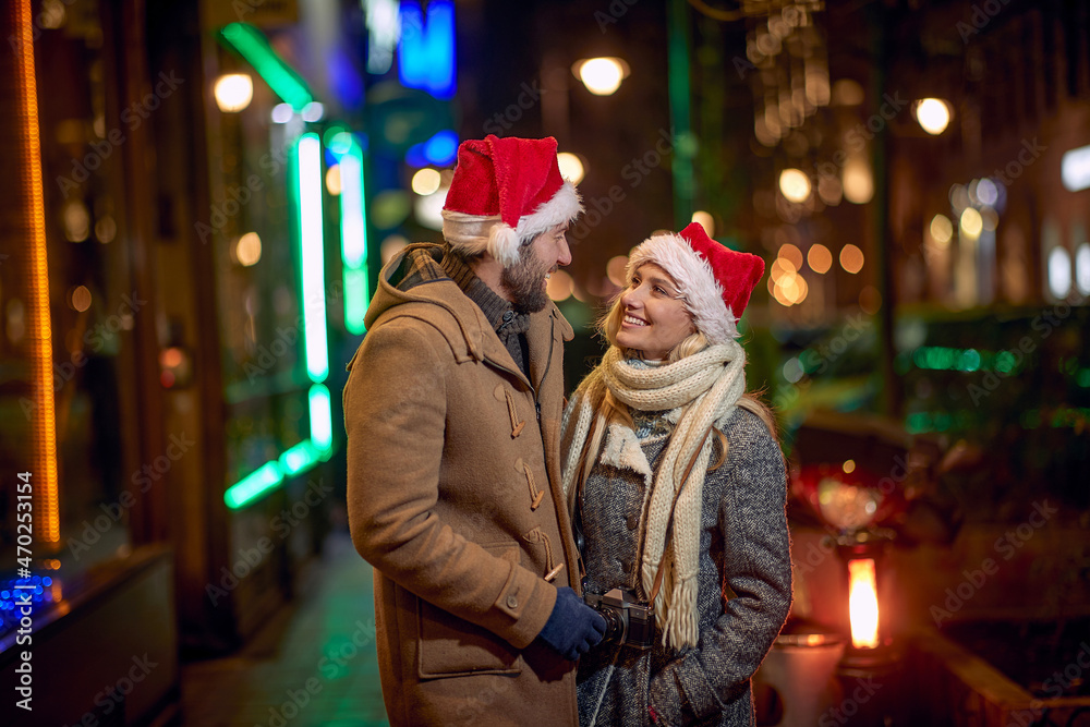Young couple in santa hat walking in winter city