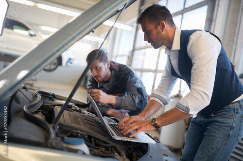 Men mechanics check the diagnostics on laptop at car