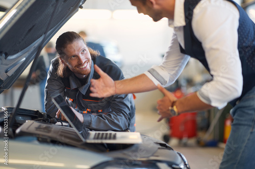 Mechanic using laptop on car. professional worker repairs auto photo