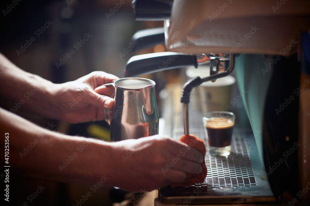 A barman is cleaning an espresso apparatus after using it. Coffee, beverage, bar