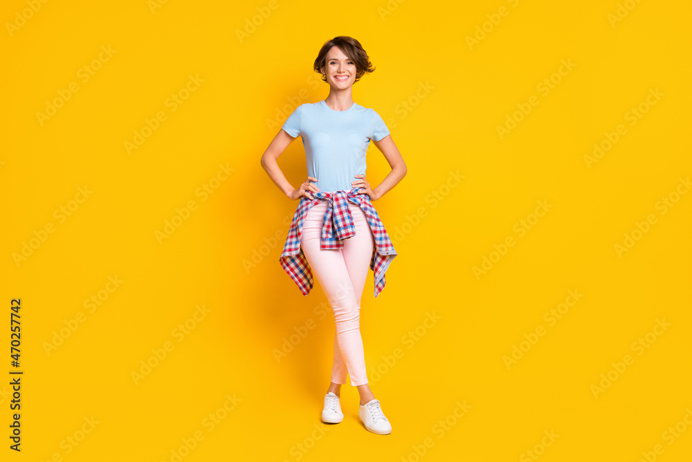 Full length photo portrait of smiling woman with tight waist shirt isolated on vivid yellow colored background