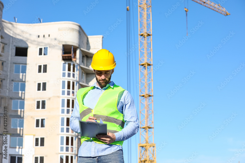 Construction worker writing in clipboard outdoors Construction worker writing in clipboard outdoors