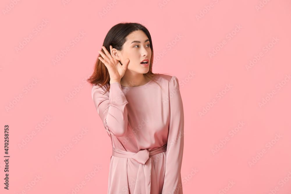 Young Asian woman trying to hear something on color background Young Asian woman trying to hear something on color background