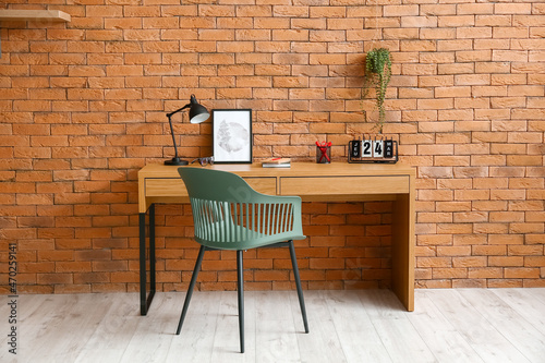 Comfortable workplace near brown brick wall in interior of room