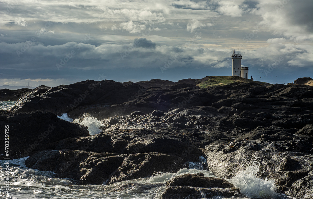 lighthouse on rocky coast and blue sky with clouds