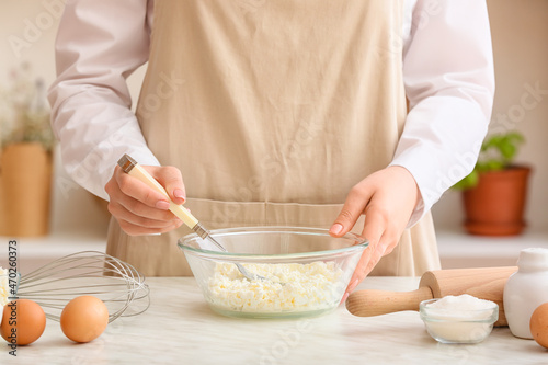 Young woman cooking delicious dumplings on light background