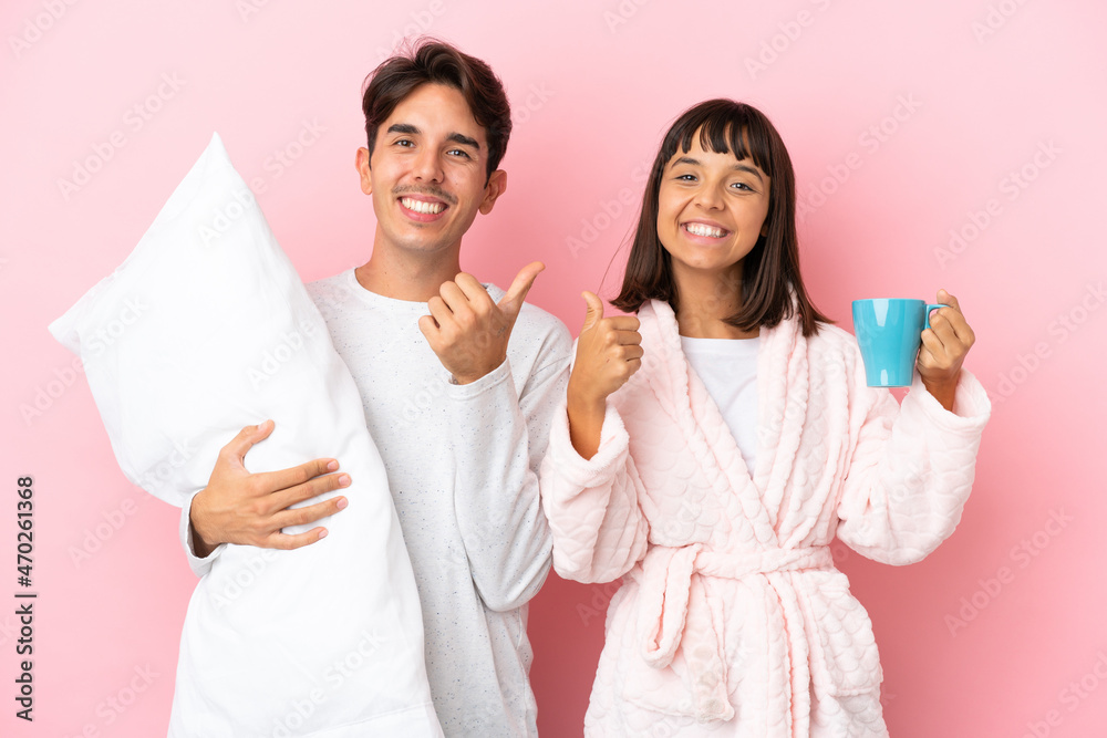 Young couple in pajamas isolated on pink background giving a thumbs up gesture with both hands and smiling Young couple in pajamas isolated on pink background giving a thumbs up gesture with both hands and smiling