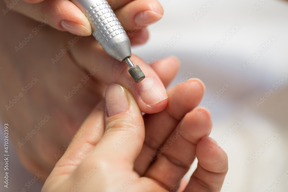 Close-up of manicurist doing hardware manicure to a young beautiful girl in the spa salon. Hardware manicure. Concept of body care Close-up of manicurist doing hardware manicure to a young beautiful girl in the spa salon. Hardware manicure. Concept of body care