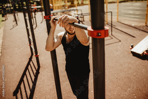 A young man goes in for sports on the sports ground, on the streets of the city. Good physique. You can add text. Use for advertising. It's a warm summer day outside
