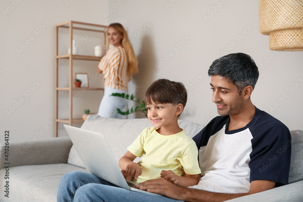 Little boy with his father using laptop on sofa at home Little boy with his father using laptop on sofa at home