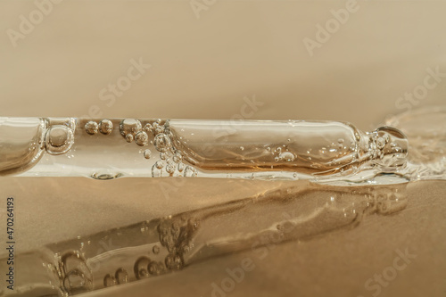The texture of serum or oil with a pipette on a beige background.