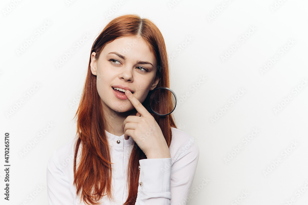 cheerful red-haired woman holding a magnifying glass near her face cheerful red-haired woman holding a magnifying glass near her face