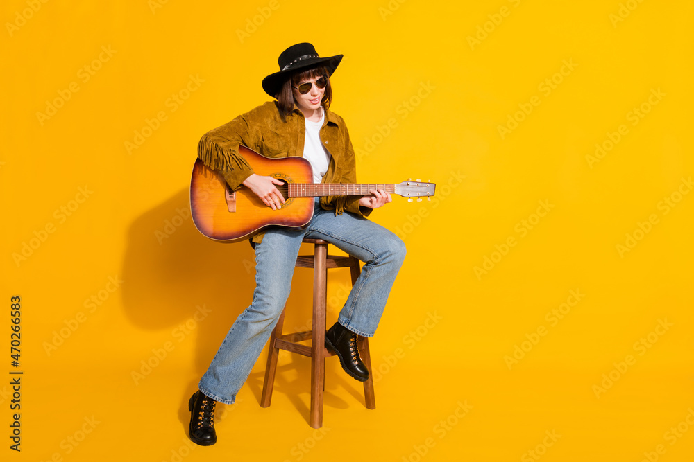 Naklejka premium Photo of pretty adorable lady wear cowgirl outfit glasses headwear playing guitar singing empty space isolated yellow color background
