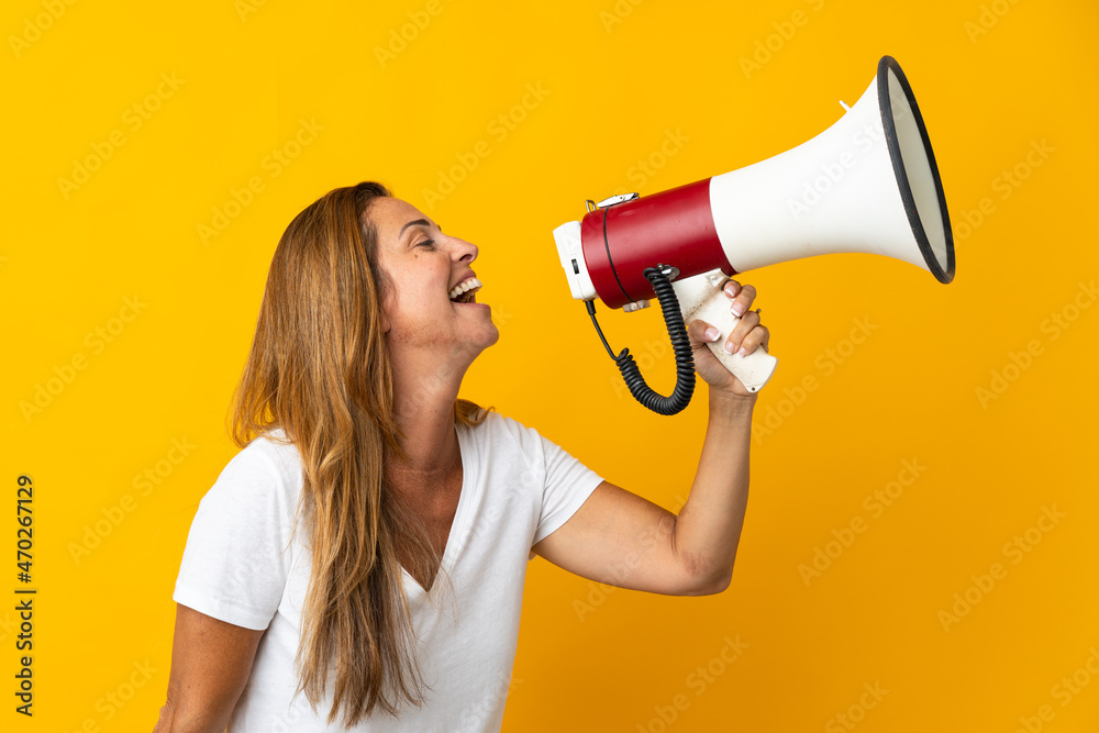 Middle age brazilian woman isolated on yellow background shouting through a megaphone to announce something in lateral position Middle age brazilian woman isolated on yellow background shouting through a megaphone to announce something in lateral position