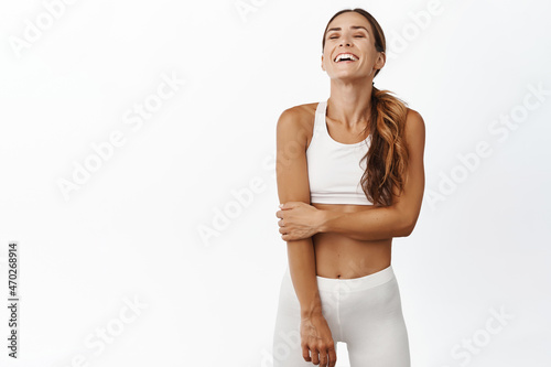 Happy sportswoman 30 years old, wearing sportsbra and leggings, laughing and smiling, enjoying active and healthy sport lifestyle, white background