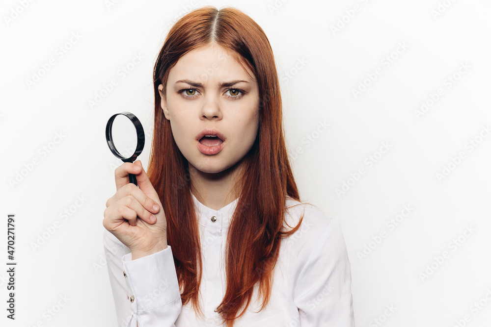 cheerful red-haired woman holding a magnifying glass near her face cheerful red-haired woman holding a magnifying glass near her face