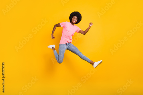 Full size profile photo of active millennial lady jump wear pink t-shirt jeans isolated on yellow color background