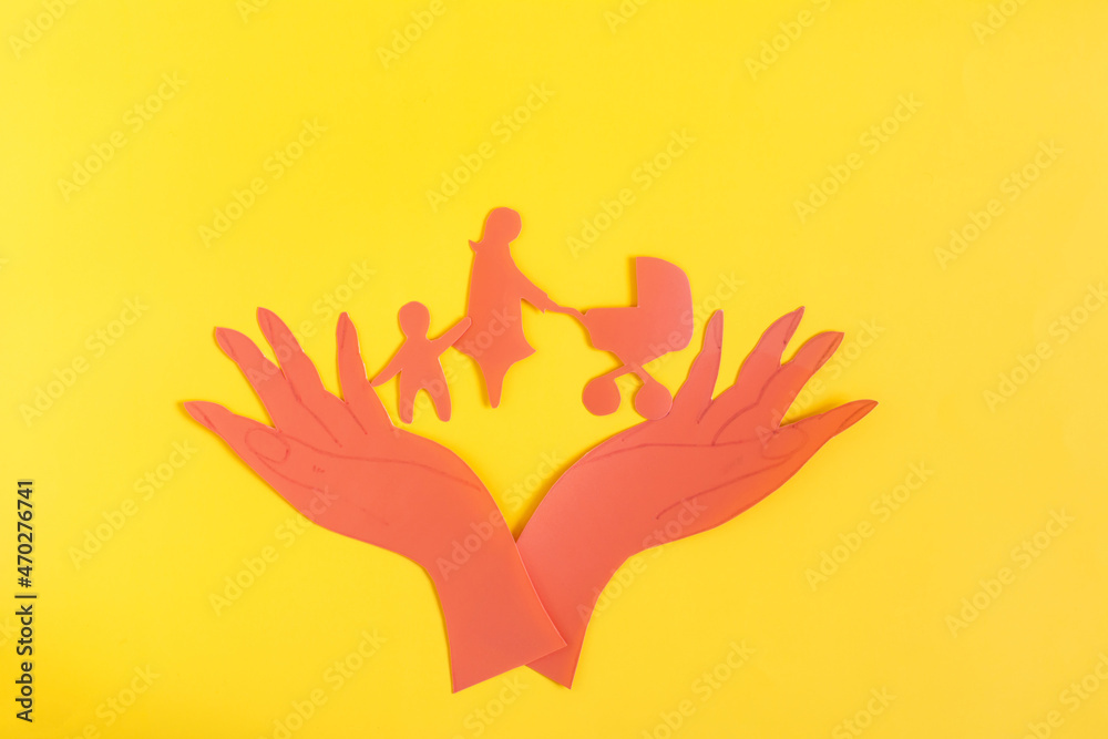 Cardboard figurines open palms of hands hold a woman with a stroller and a child. The concept of family and child protection Cardboard figurines open palms of hands hold a woman with a stroller and a child. The concept of family and child protection
