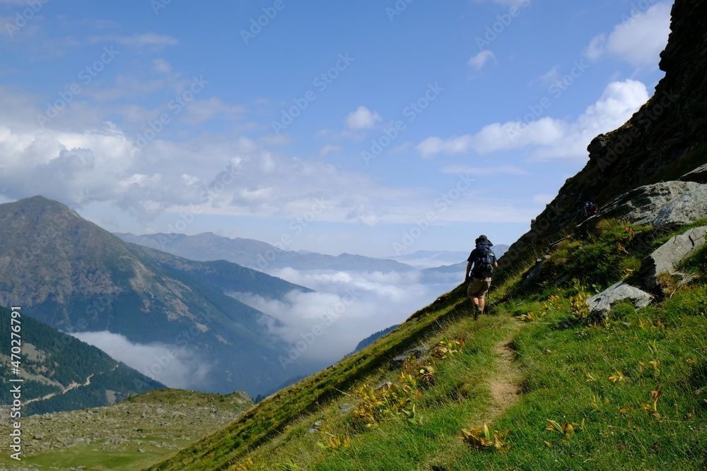 Beautiful mountain view above clouds during hiking on peak Djeravica (Gjerovica) - the highest peak of Kosovo. Silhouette of lonely tourist on trail. Albanian Alps, Peaks of Balkans