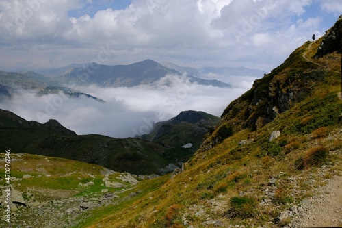 Beautiful mountain view above clouds during hiking on peak Djeravica (Gjerovica) - the highest peak of Kosovo. Silhouette of lonely tourist on trail. Albanian Alps, Peaks of Balkans