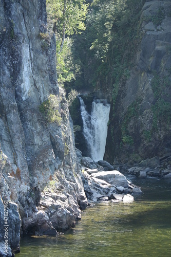 Teletskoye Lake in the Altai Mountains. The water glistens in the sun. Trees grow on the mountain. Mountain river and waterfall.