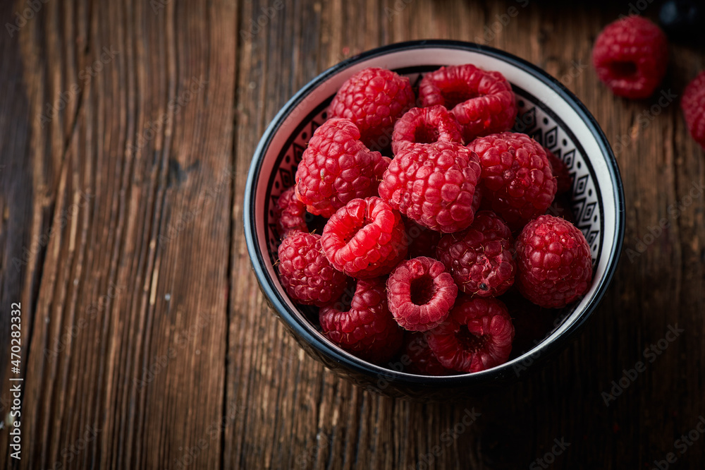 Raspberry in a ceramic bowl over wooden rustic background Raspberry in a ceramic bowl over wooden rustic background