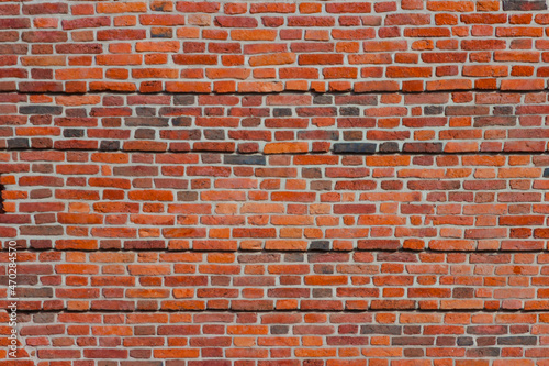 A wide brick blank wall of an old building. Uneven brickwork on a large wall.