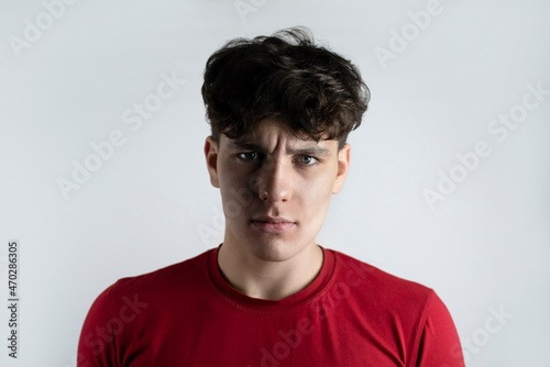 Dramatic portrait of a handsome teenage boy, he has an angry face, half face in the light the other half in the shadows. The guy struggles with negative emotions on their own