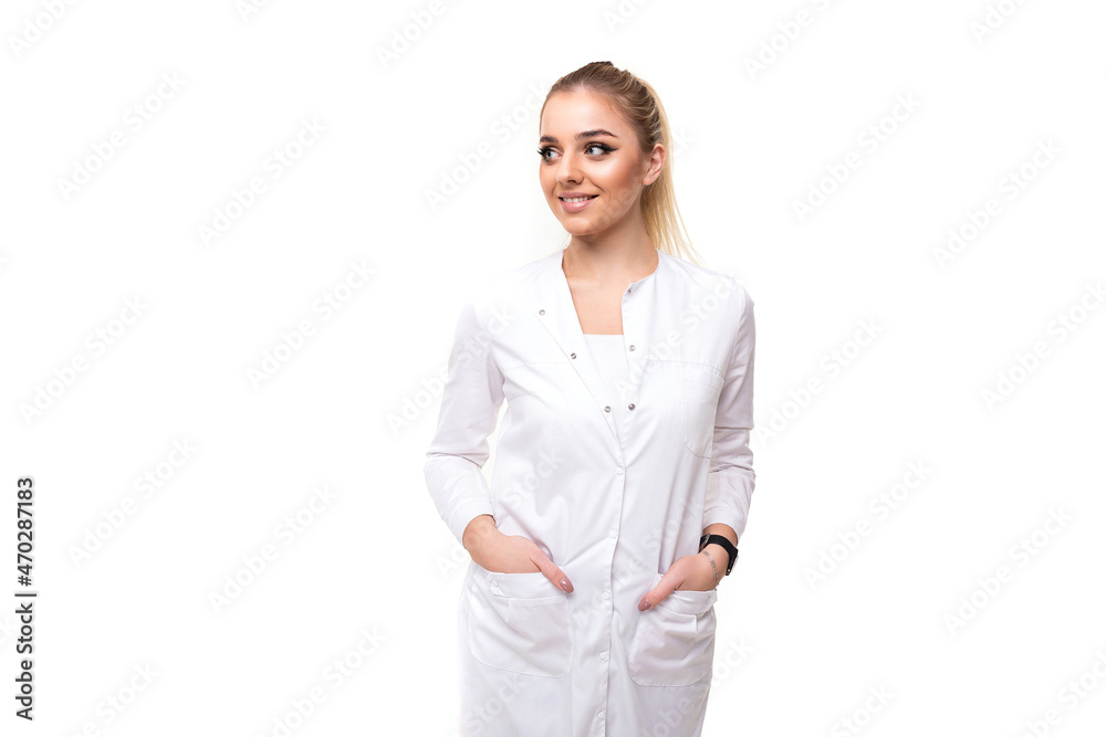 Photo of a beautiful pretty attractive positive smiling young blonde woman with a ponytail and makeup in a white medical coat of a nurse isolated on a white background with free and copy space for Photo of a beautiful pretty attractive positive smiling young blonde woman with a ponytail and makeup in a white medical coat of a nurse isolated on a white background with free and copy space for