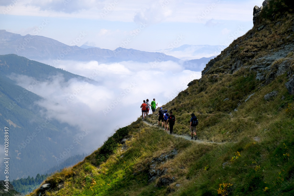 Beautiful mountain view above clouds during hiking on peak Djeravica (Gjerovica) - the highest peak of Kosovo. Group of tourists on trail. Albanian Alps, Peaks of Balkans