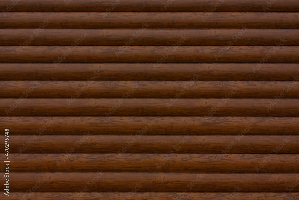 The wall is made of horizontal wooden beams of brown color. Wooden texture. Brown background. The wall is made of horizontal wooden beams of brown color. Wooden texture. Brown background.