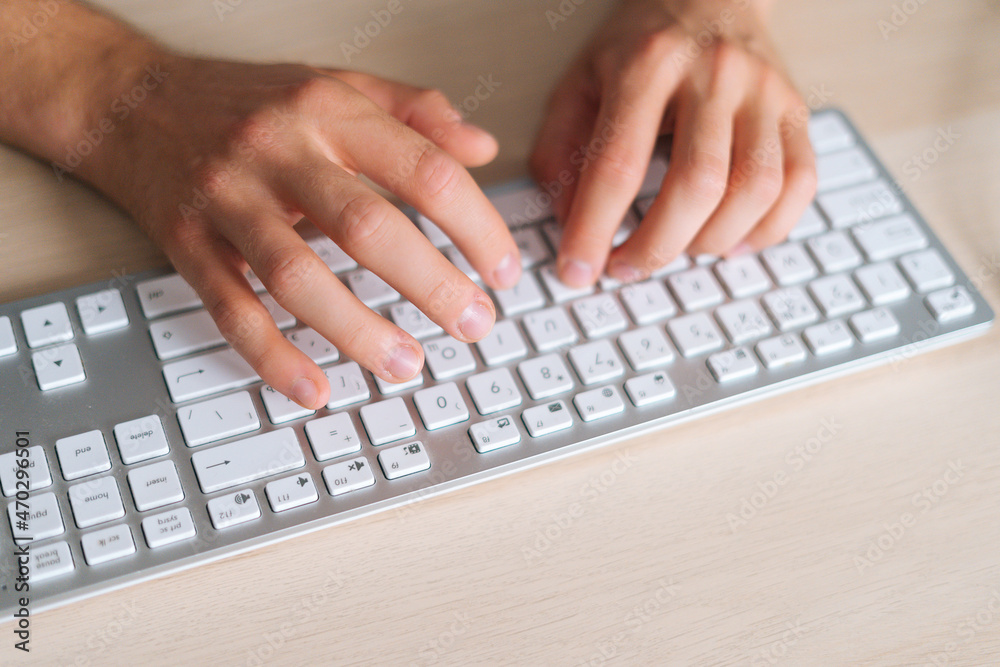 Close-up top view hands of unrecognizable business man using wireless computer keyboard sitting at light working desk in home office, closeup, selective focus. Close-up top view hands of unrecognizable business man using wireless computer keyboard sitting at light working desk in home office, closeup, selective focus.