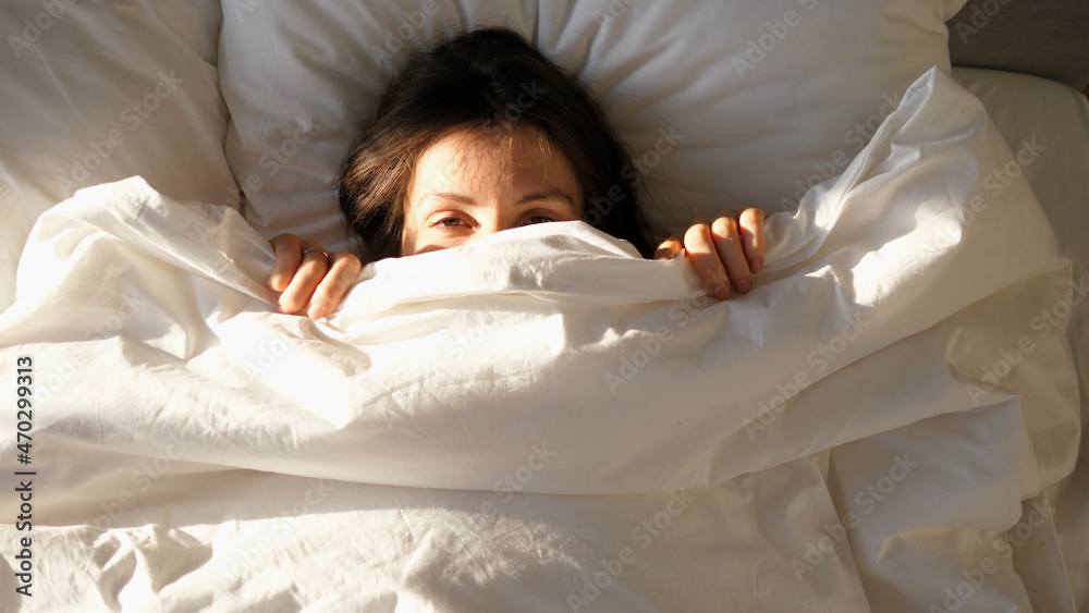 Portrait of young happy beautiful woman smiling in front of the camera lying in bed early in the morning after waking up. Cute beautiful girl looks happy in the bedroom on the pillow. Portrait of young happy beautiful woman smiling in front of the camera lying in bed early in the morning after waking up. Cute beautiful girl looks happy in the bedroom on the pillow.