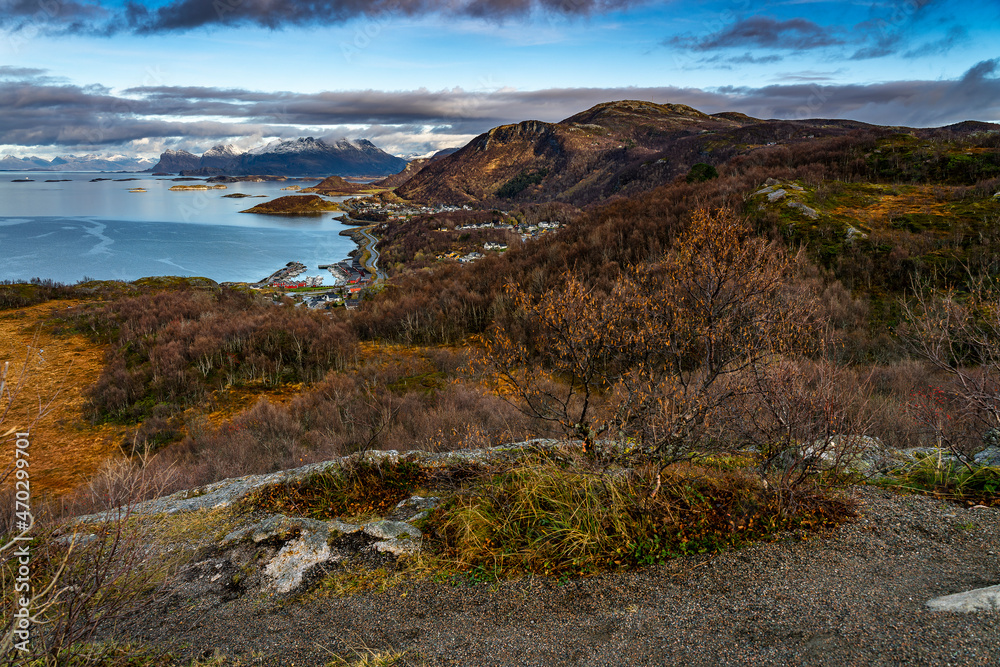 Kurven der Küstenstrasse in Norwegen zwischen Bodø und Storvollen, vom Rønvikfjell, Linken aus gesehen. Tolle Aussicht im Herbst mit bunten Bäumen und Büschen, Schnee in den Bergen. 