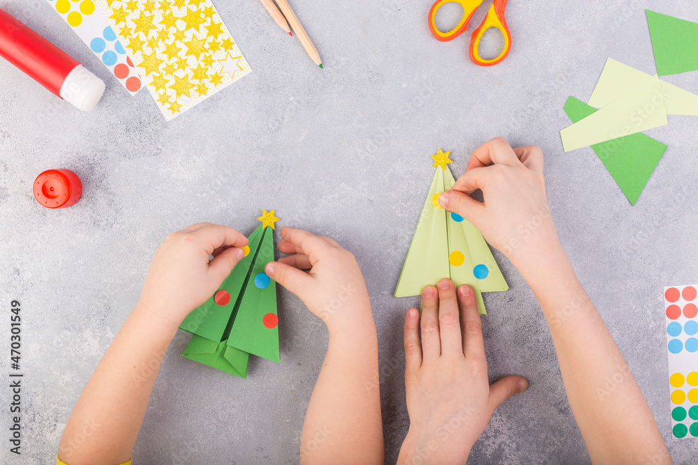 The children decorate paper tree origami. Christmas paper collage. Made