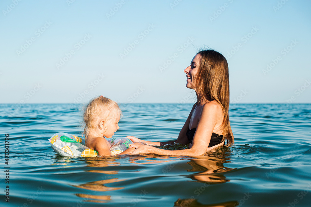 Child with a circle and mom swim in the sea