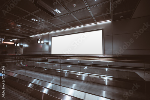 A big rectangular glowing blank neon billboard template near two travelators of a modern dark airport terminal; a mockup of an empty white banner indoors of a shopping mall next to two moving walkways