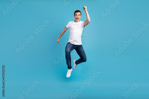 Full length photo of young cheerful guy go walk run jump up hurry fast isolated over blue color background