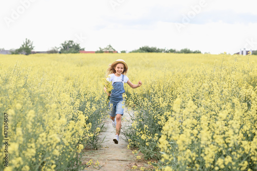 little girl in a rapeseed field holding flowers