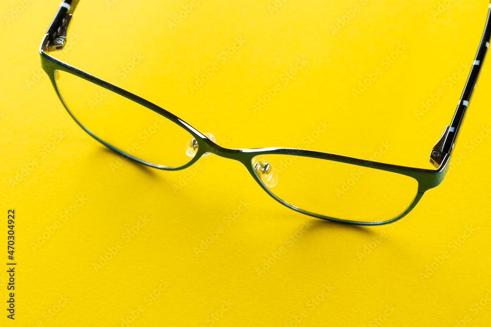 Stylish eyeglasses over yellow background. Glasses selection, eye test, vision examination at optician, fashion accessories concept. Top view, flat lay. Stylish eyeglasses over yellow background. Glasses selection, eye test, vision examination at optician, fashion accessories concept. Top view, flat lay.